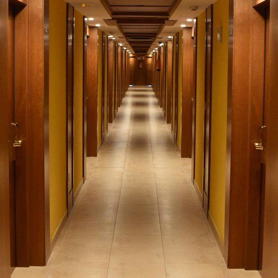 Warmly lit hotel corridor with wooden doors and soft ambient lighting, no guests visible