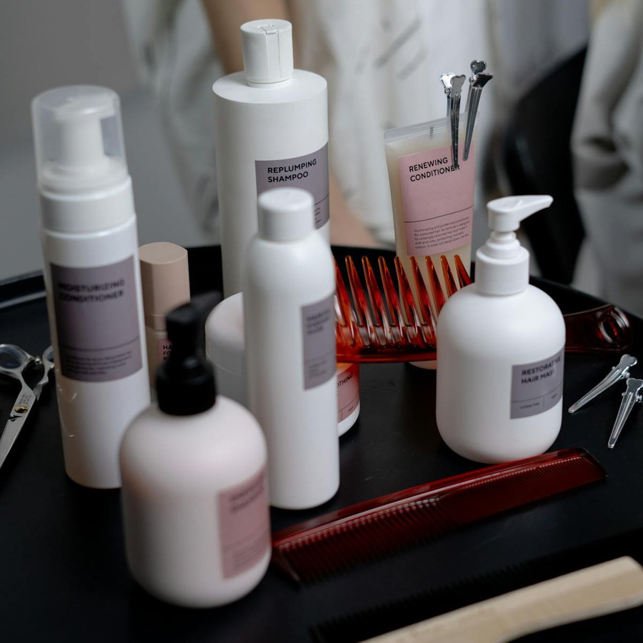 Hotel shampoo and toiletry bottles arranged neatly with combs on a bathroom shelf